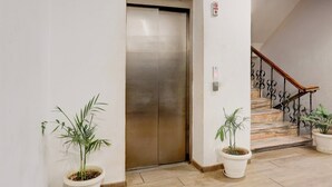 An elevator, a staircase with a wrought iron railing, and potted plants. - Townhouse Prayagraj Near Railway Station Formerly Santosh Palace (Prayagraj)