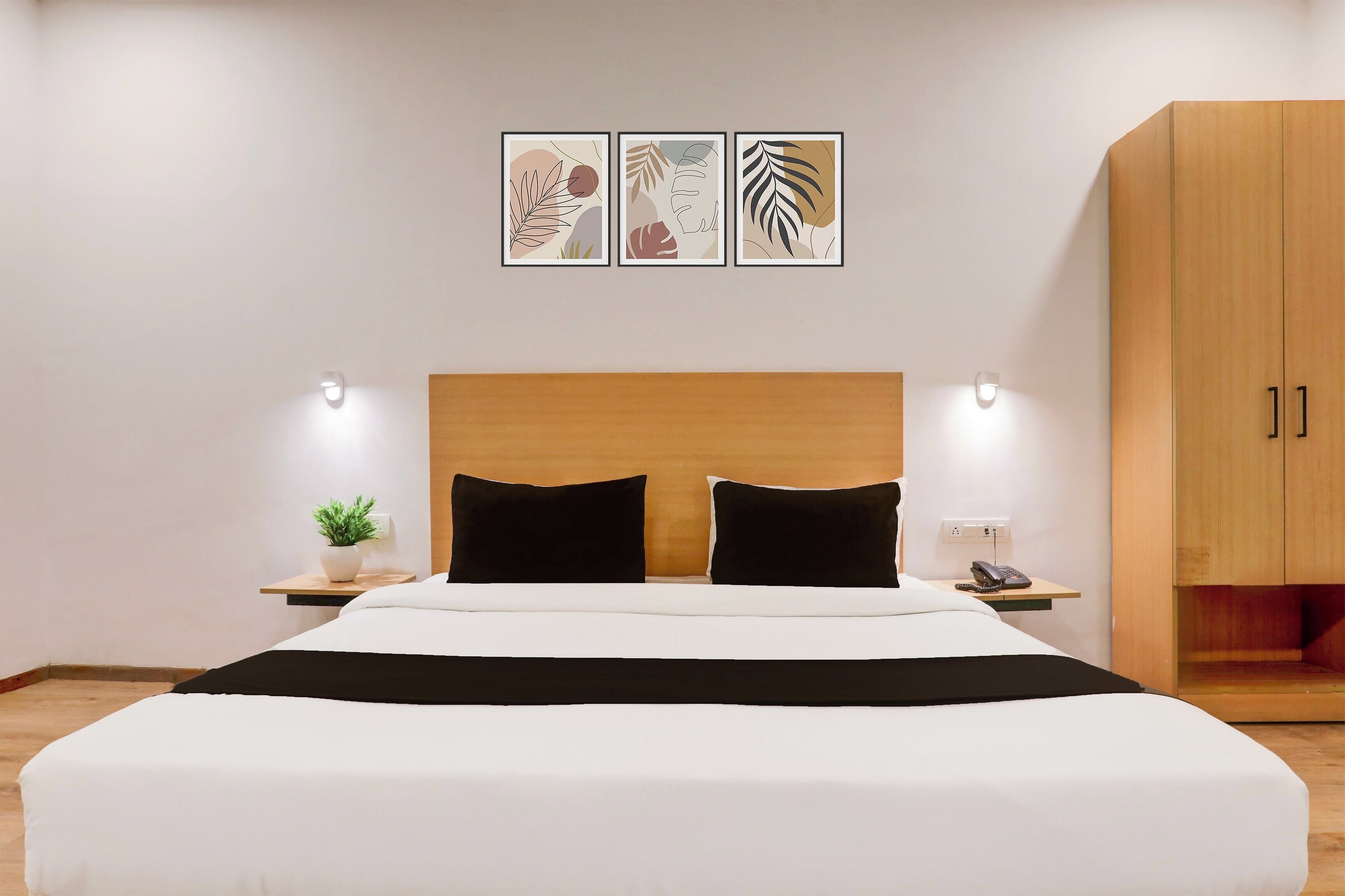 A hotel room with a bed, bedside tables, a nightstand, a telephone, and a wardrobe.