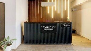 A reception desk with a 'Company-Serviced' sign, a potted plant, and a modern ceiling design. - Townhouse Prayagraj Near Railway Station Formerly Santosh Palace (Prayagraj)