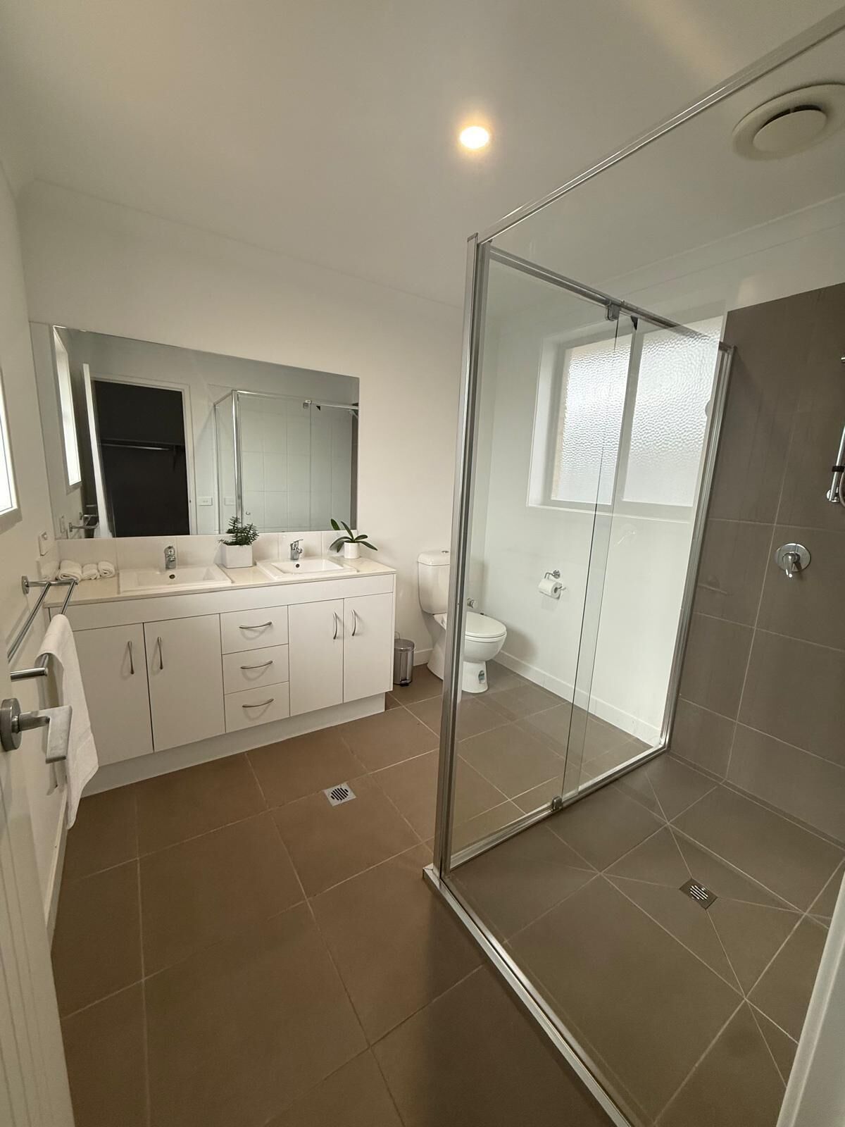 A modern bathroom with a glass shower enclosure, a white sink, and a toilet.