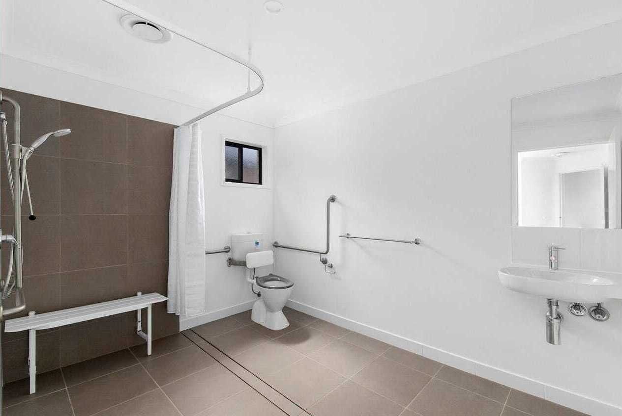 A modern bathroom with a shower, toilet, and sink.