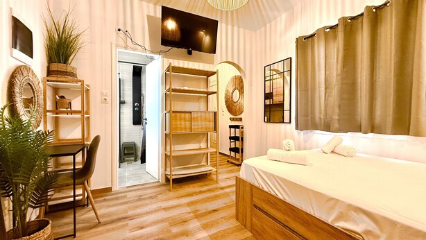 Ein Hotelzimmer mit Bett, Schreibtisch, Stuhl, Fernseher, Kleiderschrank und Bad.