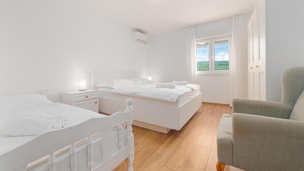 Quarto com duas camas, uma cadeira e uma janela com vista.