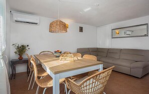 A dining area with a table, chairs, a hanging light fixture, a sofa, and a wall-mounted air conditioner. - Nice home in Cista velika (Cista velika)