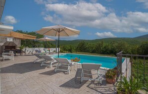 A poolside area with lounge chairs, an umbrella, and a barbecue grill. - Nice home in Cista velika (Cista velika)