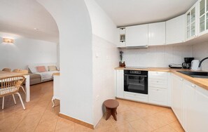 A compact kitchen with white cabinets, a built-in oven, and a small stool. - Nice home in Cista velika (Cista velika)