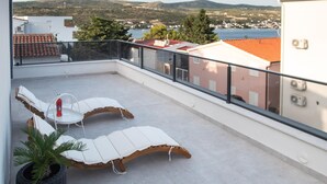 Ein Balkon mit zwei Liegestühlen, einem kleinen Tisch und einem Blumentopf.
