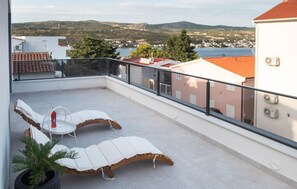 Ein Balkon mit zwei Liegestühlen, einem kleinen Tisch und einem Blumentopf.