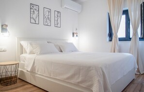 A bedroom with a bed, bedside tables, a wall-mounted air conditioner, and a window with curtains. - Nice home in Rogoznica (Rogoznica)