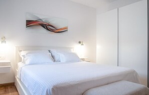 Una habitación de hotel con cama, mesitas de noche, una obra de arte en la pared y un armario.
