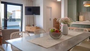 Ein moderner Essbereich mit einem Tisch für zwei Personen, einer Obstschale und einer Vase mit Blumen.