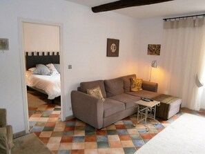 A living room with a sofa, a small table, and a bed in the background. - The perfect getaway in Saint-Chinian, home to the famous wine (Saint-Chinian)