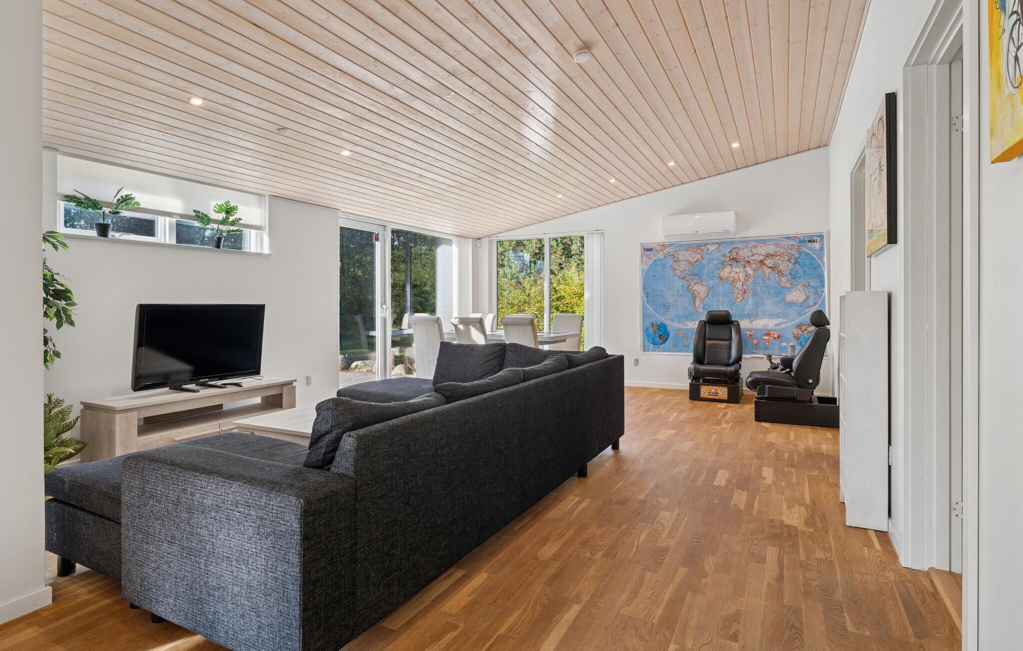Un salon moderne avec un grand canapé, un téléviseur à écran plat et une carte du monde accrochée au mur.