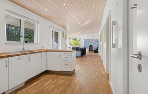 A modern kitchen with wooden cabinets and a wooden countertop, a dining area with a sofa and chairs, and a large world map on the wall. - Awesome home in Bording with sauna (Bording)