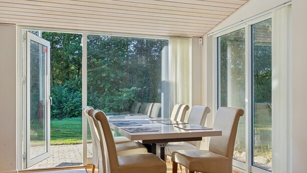 A dining area with a table and chairs, large glass doors leading to a garden. - Awesome home in Bording with sauna (Bording)