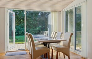 Ein Essbereich mit Tisch und Stühlen, große Glastüren führen in einen Garten.