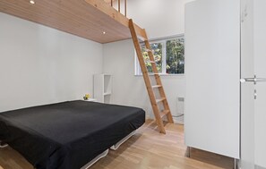 A bedroom with a bed, a white wardrobe, a wooden ladder, a white speaker, and a window with a view of trees. - Awesome home in Bording with sauna (Bording)