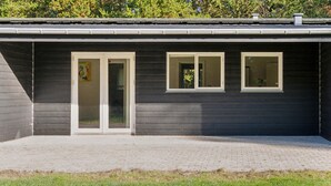 A modern building with a dark exterior, a paved patio, and three windows. - Awesome home in Bording with sauna (Bording)