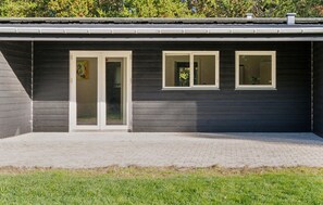 A modern building with a dark exterior, a paved patio, and three windows. - Awesome home in Bording with sauna (Bording)