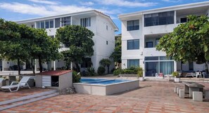 A modern building with a swimming pool, outdoor seating, and greenery. - Beachfront 2-bedroom condo in La Libertad. (La Libertad)