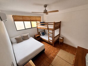 A bunk bed with a desk, a ceiling fan, and a window with blinds. - Beachfront 2-bedroom condo in La Libertad. (La Libertad)