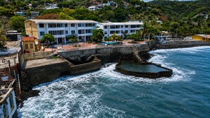 A coastal hotel with a sea view, a swimming pool, and a rocky breakwater. - Beachfront 2-bedroom condo in La Libertad. (La Libertad)