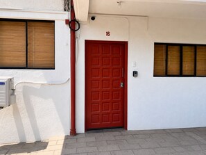 A red door with the number 16, a white wall, and a window with blinds. - Beachfront 2-bedroom condo in La Libertad. (La Libertad)