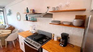 A kitchen with a stove, coffee maker, and various kitchenware. - Beachfront 2-bedroom condo in La Libertad. (La Libertad)
