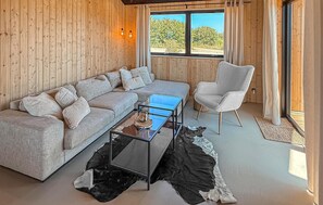 A wooden-paneled room with a sofa, a chair, a glass coffee table, and a view of the outdoors. - Lovely home in Børkop with sauna (Børkop)