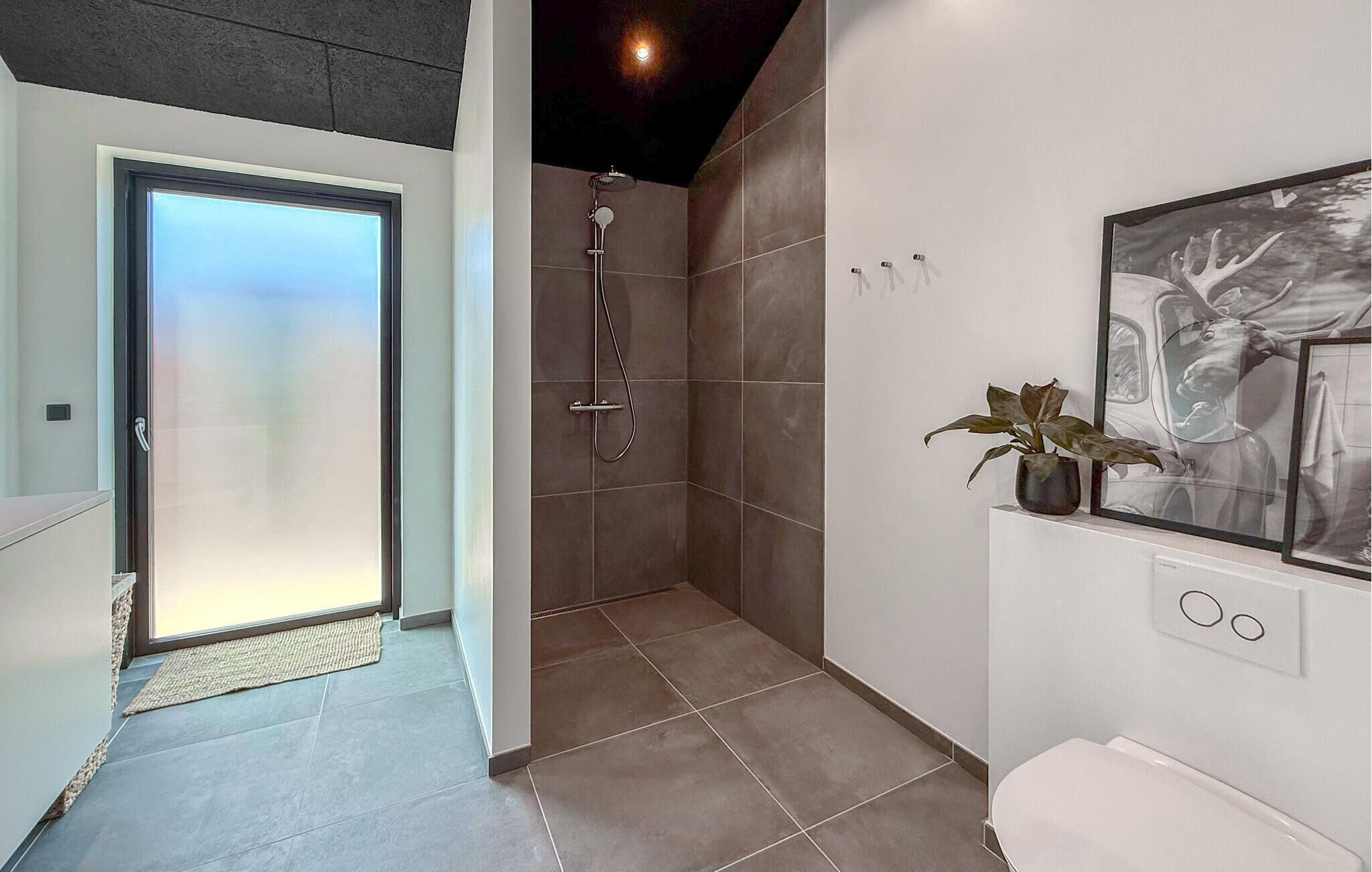 A modern bathroom with a shower, a toilet, and a sink.