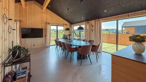 Un comedor moderno con una mesa redonda y sillas, paredes de madera y ventanas amplias.