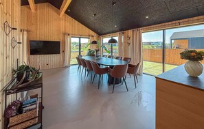 A modern dining area with a round table and chairs, wooden walls, and large windows. - Lovely home in Børkop with sauna (Børkop)