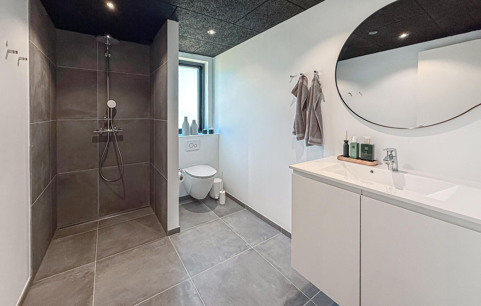 Une salle de bain moderne équipée d’une douche, de toilettes et d’un lavabo.