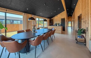 Ein modernes Interieur mit einem zentralen Esstisch, Holzwänden und einer Küchenzeile.