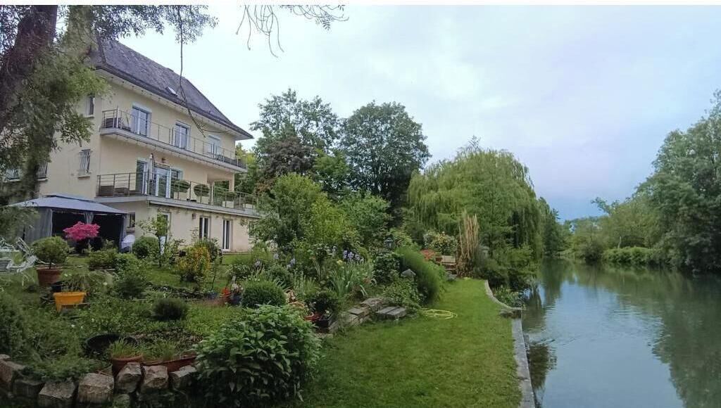 Une maison à deux étages avec un jardin et un canal.