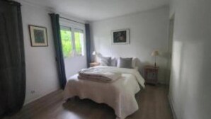 Een slaapkamer met een bed, een nachtkastje, een lamp en twee afbeeldingen in een lijst aan de muur.
