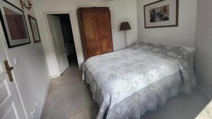 Quarto com cama, guarda-roupa, porta e abajur.