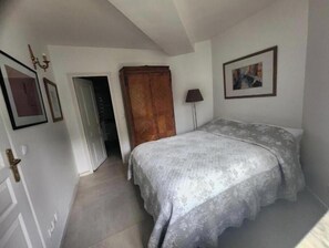 A bedroom with a bed, a wardrobe, a door, and a lamp. - Les Rives de Montigny-sur-Loing: 3-Bedroom Apartment (Montigny-sur-Loing)