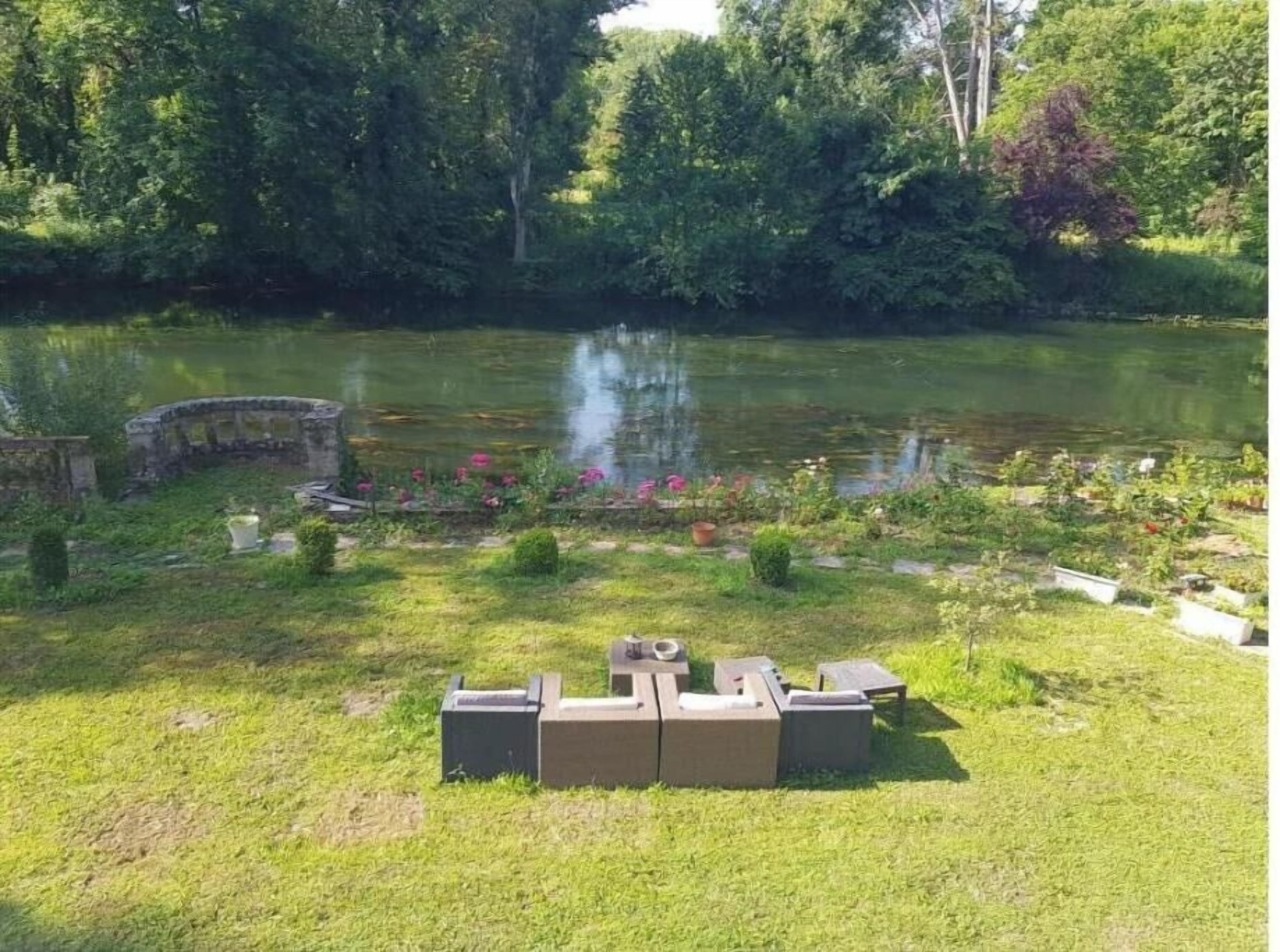 A garden with a pond, a stone bridge, and outdoor furniture.