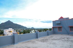 A rooftop terrace with a view of a mountain and surrounding buildings. - Sri Mahadeepam Residency (Tiruvannamalai)