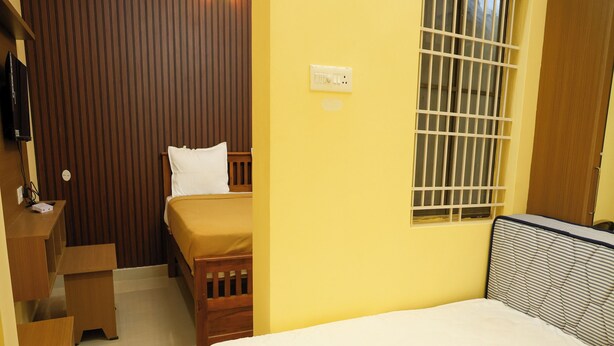 A compact room with a bed, a small desk, and a window with bars.
