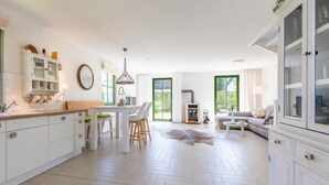 Eine geräumige Küche mit Essbereich, Kamin und einer Couch in einem hellen, modernen Ambiente.