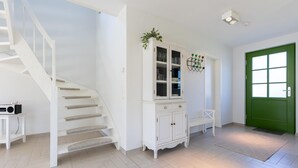Eine Treppe, ein weißer Schrank mit Glastüren, eine grüne Tür und ein weißer Stuhl.