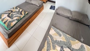 Una habitación con dos camas, una mesita de madera y una colcha estampada.