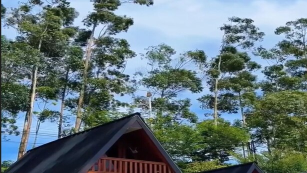 Una hilera de cabañas tipo tienda de campaña con base de piedra, barandillas de madera y un cielo despejado al fondo.