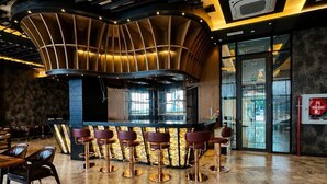Un área de bar moderna con techo curvo, barra y varios taburetes.
