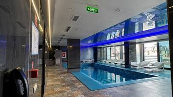 En hotellobby med ett poolområde, en receptionsdisk och en tydlig utrymningsskylt.