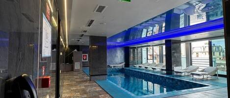 A hotel lobby with a pool area, a reception desk, and a clear exit sign.