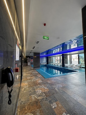 A hotel lobby with a pool area, a reception desk, and a clear exit sign. - The New Jai Son (Kobuleti)