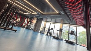 Un gimnasio con equipamiento de ejercicio y amplias ventanas.